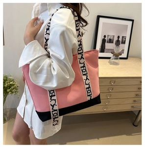Détail du sac cabas en toile rose et noir avec anses lettrées dans un décor intérieur
