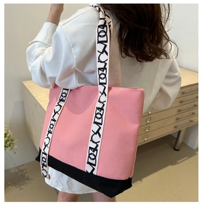 Détail d'un sac cabas en toile rose et noir porté, avec anses à motifs modernes