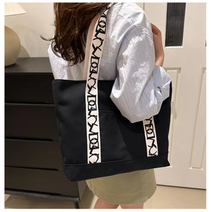 Détail du grand sac cabas noir en toile avec anses beiges à motifs et design spacieux