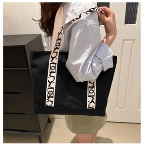 Détail du grand sac cabas noir avec bandoulière large écrue aux motifs de lettres d'art