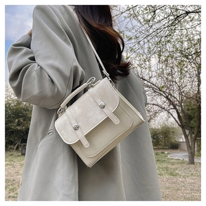Detail of cream PU leather crossbody bag worn by a model in a natural outdoor setting