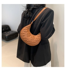 Detail of clover embossed pattern on high-quality brown crescent shoulder bag