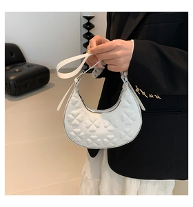Detail of white half-moon hobo bag with embossed clover pattern and silver hardware