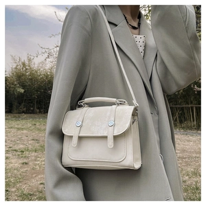 Off-white crossbody square bag featuring dual silver metal buckles and a top handle