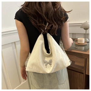 Vue détaillée du sac seau blanc plissé avec papillon en métal argenté et bandoulière