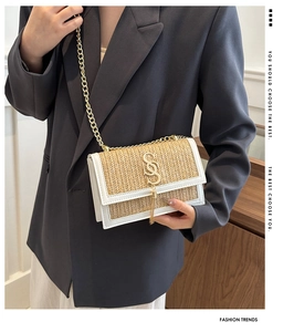 Detail of woven straw shoulder bag with gold SS logo, fringe charm and chain strap