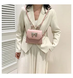 Detailed view of pink mini bow bag with silver metallic knot and matte leather finish