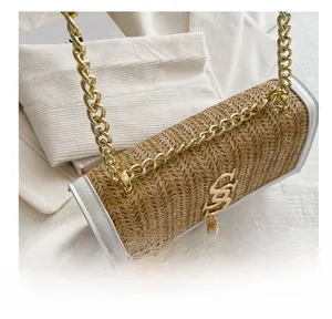 Detailed close-up of woven straw handbag with gold chain strap and metal logo