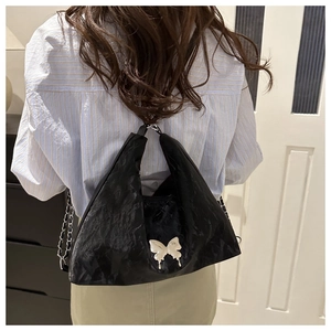 Mannequin portant un sac à bandoulière froncé noir avec ornement papillon blanc et chaîne