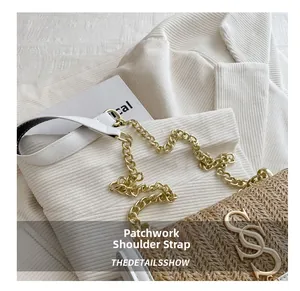 Close-up of woven straw bag with S-shaped gold logo and stitched chain leather strap