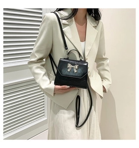 Detailed shot of black mini square bag with silver bow buckle and adjustable strap