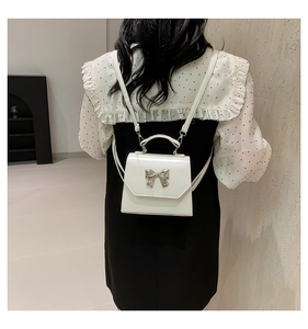 Rear view of a white mini bow backpack on a model showing size and shoulder strap detail