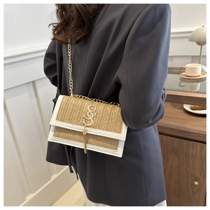 Détail du sac bandoulière en paille tressée avec bordure blanche et pompon doré