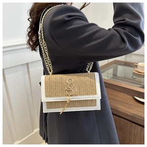 Détail du sac bandoulière en paille tressée avec chaîne dorée et gland en métal