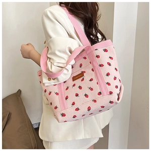 Detail shot of strawberry print corduroy tote bag showing texture and logo on pink fabric