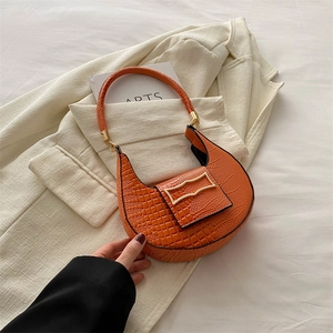 Orange croc-embossed crescent handbag with gold buckle on an elegant beige blazer