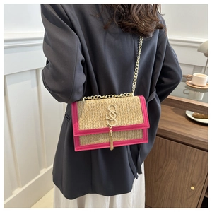Détail du sac tressé beige avec bordure en cuir fuchsia et pompon à boucle dorée en forme de S