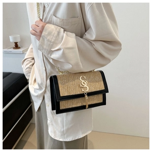 Détail du sac à bandoulière en paille tissée avec chaîne dorée et logo en métal