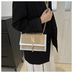 Détail du sac bandoulière en paille tressée avec bordure métallisée et chaîne dorée