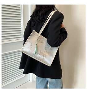 Vista dettagliata della borsa tote crema con motivi floreali e nappa verde chiaro