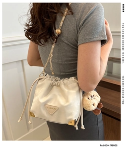 Detail of cream drawstring bucket bag with chain strap and cute plush animal charm