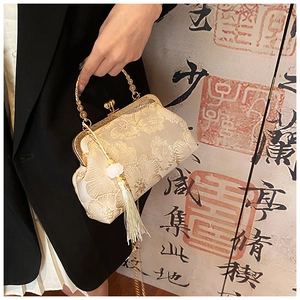 Close-up of golden silk embroidery floral handbag with traditional tassels and metal handle
