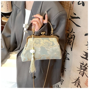 Detail of floral embroidery on light green silk bag with tassel and gold chain