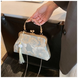 Detail of embroidered satin handbag featuring traditional tassels and a metal clasp