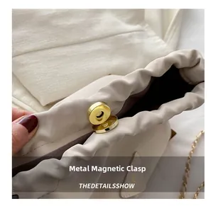 Close-up of golden magnetic buckle and interior lining on a beige bucket bag