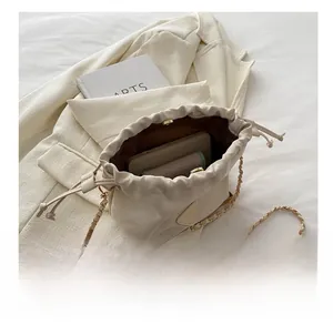 Top view of beige drawstring bucket bag showing spacious interior with metal chain strap