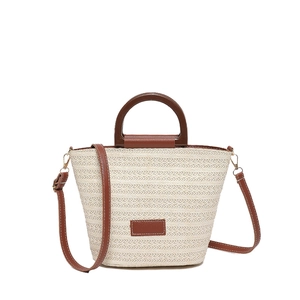 Chic woven bucket bag with cream straw texture and brown leather handles in a front view