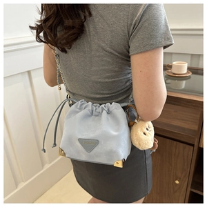 Close-up of light blue drawstring bucket bag with metal chain and plush bear charm