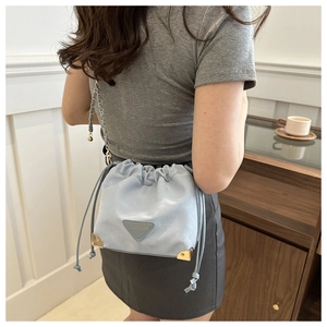Detail of light blue bucket bag with drawstring closure and golden metal corners