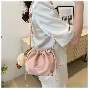 Detail of pink bucket bag with gold chain strap, metal logo and plush bear charm