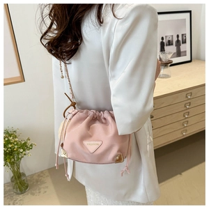 Detailed shot of pink bucket bag with gold triangle plate and plush pompom charm