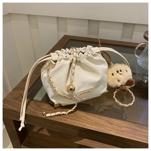 Detail of cream drawstring bucket bag with gold chain strap and cute cookie charm