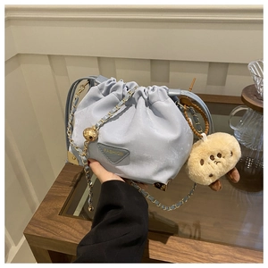 Close-up of light blue pleated bucket bag with gold chain and plush charm detail