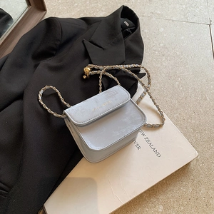 Hellblaue Mini-Umhängetasche mit goldener Kette und Kugelanhänger auf schwarzem Blazer