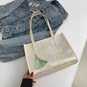Off-white floral embroidery tote bag with green tassel and traditional patterns