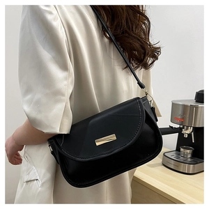 Detailansicht einer schwarzen Umhängetasche aus Leder mit goldener Verzierung am Model