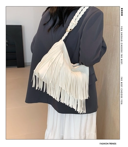 Detail of cream white leather shoulder bag featuring long tassels and woven strap design