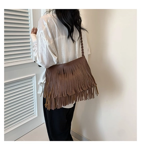 Detail of a brown tassel shoulder bag featuring fringe layers and braided strap design
