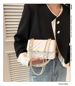 Close-up of white V-quilted faux leather crossbody bag with elegant gold chain and hardware