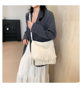 Detailed view of white fringe shoulder bag with long tassels and thin woven strap
