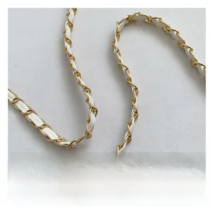 Detail of the golden metal chain interlaced with white leather strap on crossbody bag