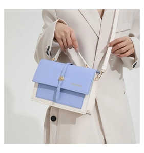Close-up of stylish contrast crossbody bag with gold hardware and wide shoulder strap