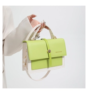 Detail view of lime green and off-white crossbody bag with gold buckle and strap hook