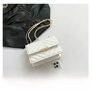 Close-up of white quilted bag with V-stitch pattern, gold chain strap and metal buckle