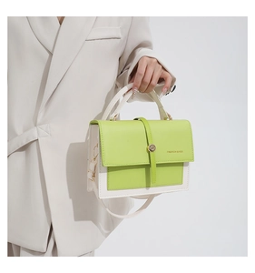 Detail of lime green and off-white leather shoulder bag with gold clasp and adjustable strap