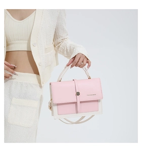 Detail view of pink and beige crossbody bag with metal buckle and fashion logo text